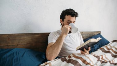 Sakallı adam onun yatak odasında yalan büyük bir kitap okuma.