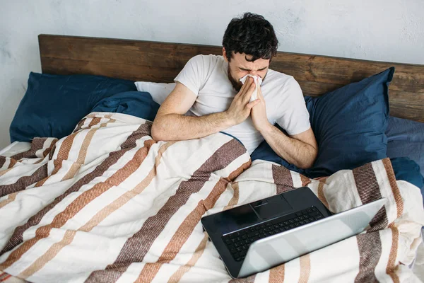 Bärtiger Mann liegt mit Laptop im Morgenbett — Stockfoto