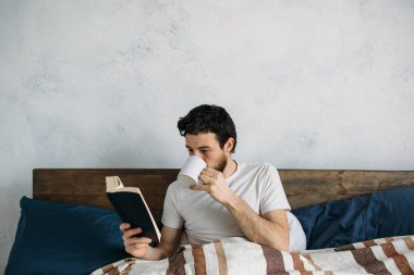 Sakallı adam onun yatak odasında yalan büyük bir kitap okuma.