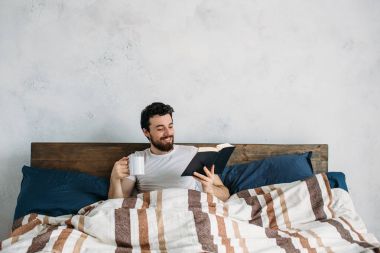 Sakallı adam onun yatak odasında yalan büyük bir kitap okuma.