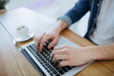Bir macbook veya dizüstü kafede çalışan adam