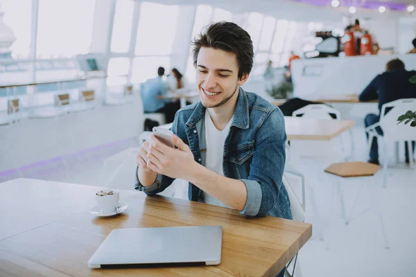 Attraktiver junger Mann oder Freiberufler mit Handy sitzt im Café und trinkt Kaffee — Stockfoto