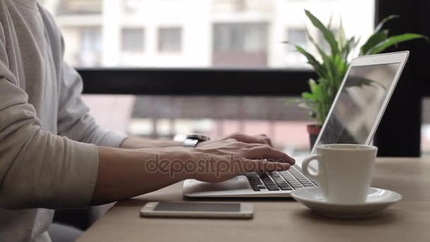 Νεαρός ελεύθερος επαγγελματίας εργάζεται πάνω σε ένα macbook στην καφετέρια — Αρχείο Βίντεο