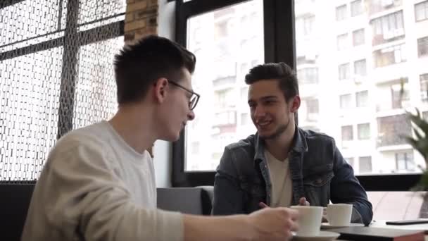 Dos amigos sentados en el café y charlando entre ellos — Vídeos de Stock