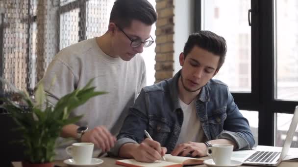 Jóvenes freelancers usando cuaderno en la cafetería para su trabajo o planes — Vídeo de stock