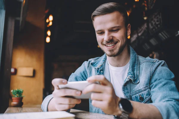 Fiatal férfi keresi a telefon, ül az étteremben — Stock Fotó