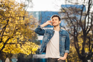 Genç adam dışarıda duruyor, telefonda konuşuyor..