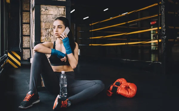 Jonge vrouw zittend op de vloer na zware training in de sportschool. — Stockfoto