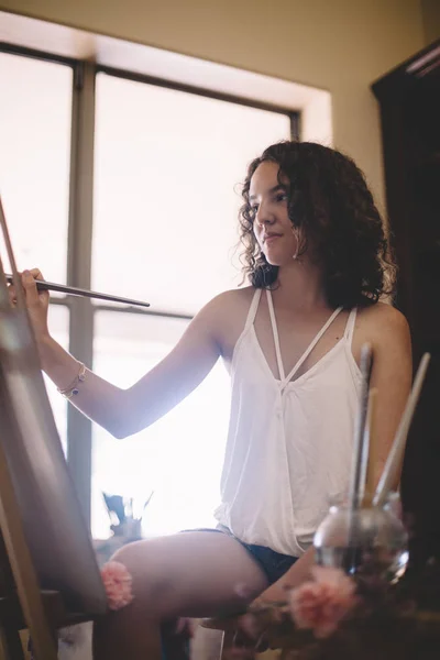 Artista menina pinta quadro em tela em estúdio — Fotografia de Stock