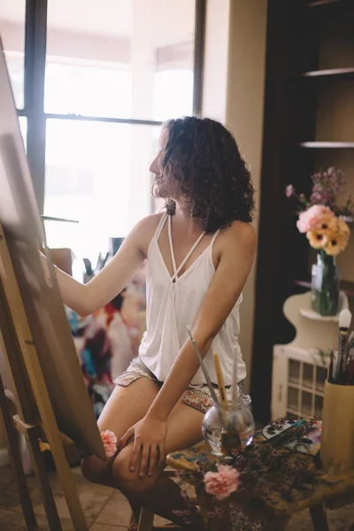 Artist girl paints picture on canvas in studio