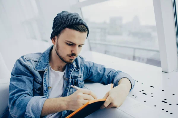 Guy is zittend op een bank en schrijven van notities — Stockfoto