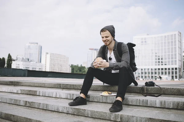 Gezgin sonra uzun yolculuk basamaklarında oturan ve burger onun elinde tutan