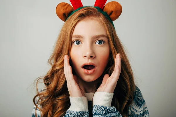 Chica con cuernos de ciervo en un suéter sonríe. Ella está sorprendida por el regalo para el nuevo año. Increíbles descuentos para Navidad y Año Nuevo . Imágenes De Stock Sin Royalties Gratis