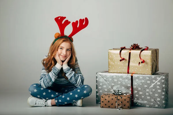 En tonåring med röda rådjurshorn i tröja köpte julklappar till föräldrar till ett lågt pris. Flickan väntar när hon kan presentera överraskningar för sina vänner för det nya året. Semesterrabatter Stockfoto