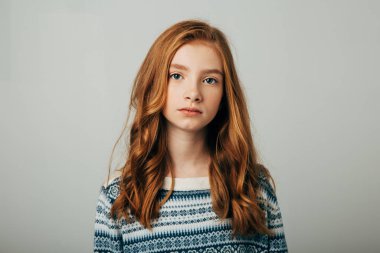 Mavi kazaklı genç kızıl saçlı bir kız kameraya bakıyor. Endişeli bir videosu olan bir kız dikkatinizi toplumun sorunlarına çekmeye çalışıyor. Beyaz arkaplanda izole et.