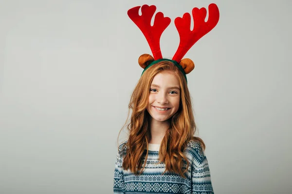 Una joven pelirroja sonríe y mira a la cámara antes de Navidad. Ella se está preparando para la celebración del nuevo año. Aislar sobre un fondo blanco . Imagen De Stock