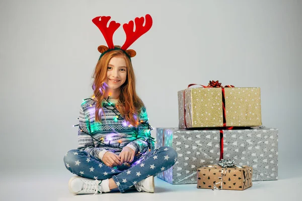 Tonåring med röda horn köpte julklappar till föräldrar till låga priser.Flickan väntar när hon kan presentera överraskningar för sina vänner för det nya året.Holiday rabatter.She insvept sig garland Stockfoto