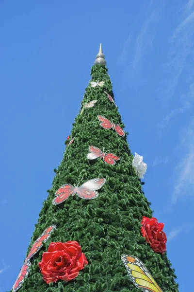 Velký umělý vánoční stromek zdobený růží a motýlů — Stock fotografie
