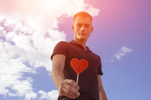 Uomo con un lecca-lecca a forma di cuore Immagine Stock