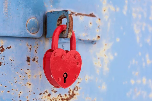 Lucchetto cuore rosso sulla porta di metallo blu Foto Stock