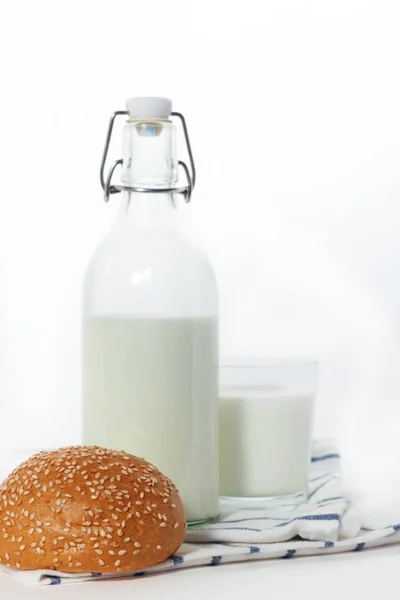 Glasflasche mit Milchglasbecher und Brot auf Serviette auf weiß — Stockfoto