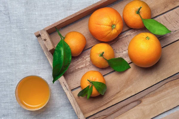 Oranges et mandarines dans une boîte en bois sur toile. Jus d'orange . Images De Stock Libres De Droits