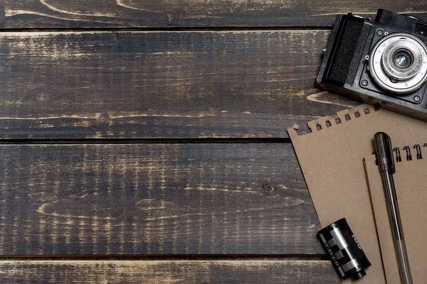 Vecchia macchina fotografica, un blocco note e un film su uno schienale di legno scuro — Foto Stock