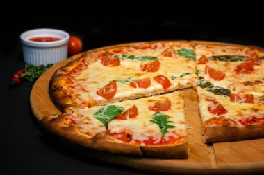 Siyah bir arka plan üzerinde parçalar halinde kesilmiş pizza