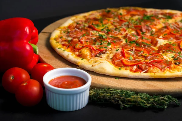 Pizza, sauce and spices on a black background