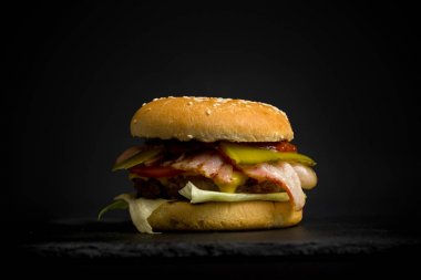 Karanlık bir arka plan üzerinde lezzetli taze hamburger close-up. Hambu