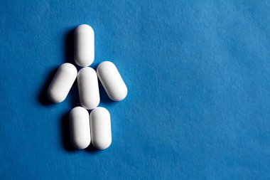 Hapları yapılmış küçük adam. Kırmızı kağıt arka plan üzerinde tıbbi tablet üzerinden duygu kukla.