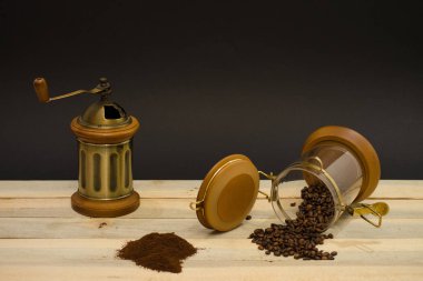 Dağınık kahve çekirdekleri zemin kahve ve el ile kahve değirmeni ahşap kurullarında ve siyah arka plan üzerine