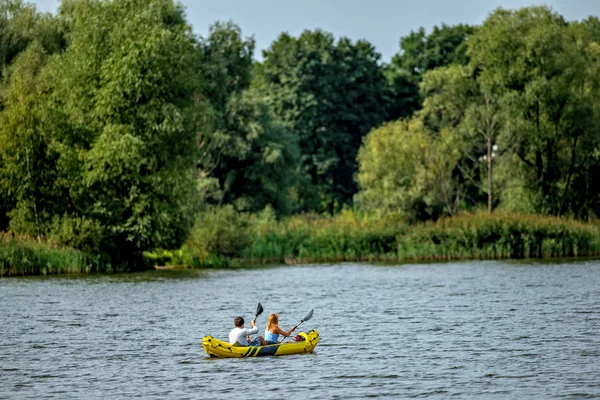カヤック 銀行の緑の森に湖や川に黄色の水増しカヤックを漕ぐカップル — ストック写真