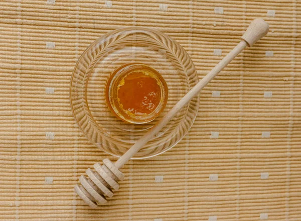 Glass jar of honey on a textile tablecloth. Glass saucer and wooden spoon, kitchen utilities. Home made organic mask ingredients. Healthy eco lifestyle. Food blog illustrations. Honey and lemon