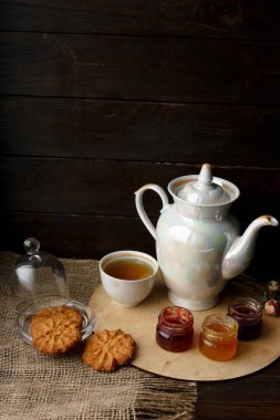 Ahşap tepsi üzerinde ev yapımı Berry üç küçük kavanoz reçel. Sağlıklı gıda fikirler. Çaydanlık ve yeşil çay bir arka plan üzerinde çay fincanı. Gül ahşap bir masa bir gümüş kaşık yanında bastırdı