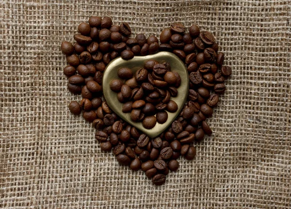Düz bir masa örtüsü üzerinde kavrulmuş kahve çekirdekleri, altın kalp şeklinde daire ve kupa ile yatıyordu. Fincan sabah espresso ve preslenmiş gül. Romantik Fikirler