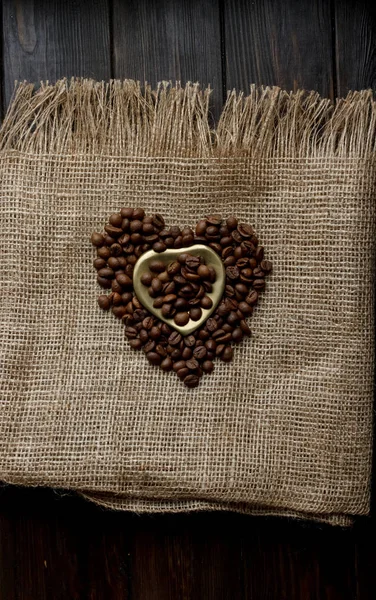 Düz bir masa örtüsü üzerinde kavrulmuş kahve çekirdekleri, altın kalp şeklinde daire ve kupa ile yatıyordu. Fincan sabah espresso ve preslenmiş gül. Romantik Fikirler