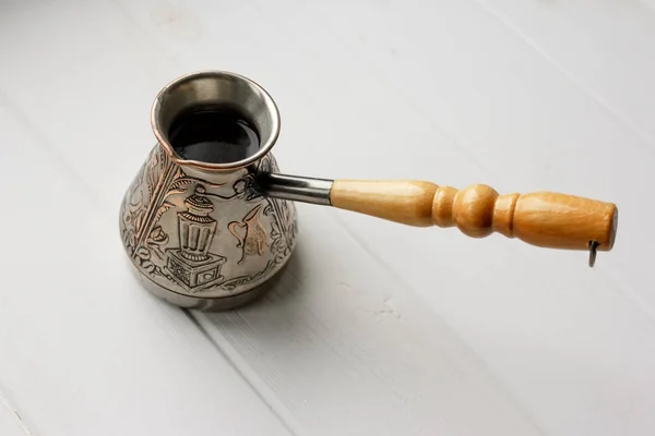 Türk kahve makinesini yüksek kaliteli arabica fasulye ile. İzole kahve Beyaz ahşap zemin üzerinde. Kahve Saati gelenekleri. Espresso, latte, cappuccino yapmak için ayarla