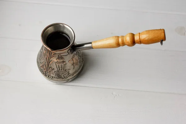 Türk kahve makinesini yüksek kaliteli arabica fasulye ile. İzole kahve Beyaz ahşap zemin üzerinde. Kahve Saati gelenekleri. Espresso, latte, cappuccino yapmak için ayarla