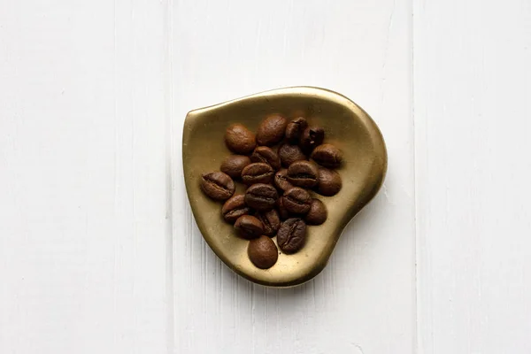 Düz bir masa örtüsü üzerinde kavrulmuş kahve çekirdekleri, altın kalp şeklinde daire ve kupa ile yatıyordu. Fincan sabah espresso ve preslenmiş gül. Romantik Fikirler