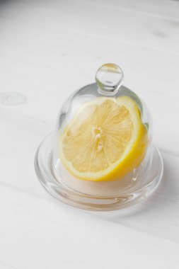 Yarısı sarı limon bir cam daire üzerinde yalan. Ahşap masa arka planda. Sarı meyve kapatın. Sağlıklı yaşam tarzı ve taze meyve suyu