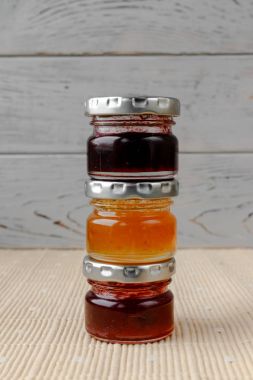 Üç küçük kavanoz meyve sıkışmaları bir masa örtüsü. Mutfak araçları. Ev yapımı reçel. Ahşap arka plan üzerinde sağlıklı tatlılar.