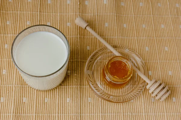 Glass jar of honey on a textile tablecloth. Glass saucer and wooden spoon, kitchen utilities. Home made organic mask ingredients. Healthy eco lifestyle. Food blog illustrations. Honey and lemon