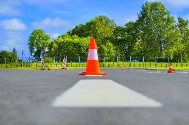Koyu asfaltta duran trafik konisi. Yol yapımında kırmızı lastik koni. Yol çalışması, park alanı. Havaalanı pistinde trafik konisi. Sürücü kursunda araba sürme eğitimi için yolda çit direkleri var..