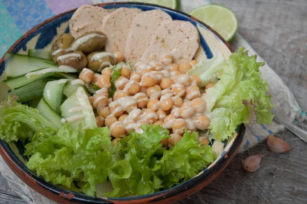 healthy salad in a bowl. olives, lime, chickpeas, paprika tofu,  cucumber  and tahini.