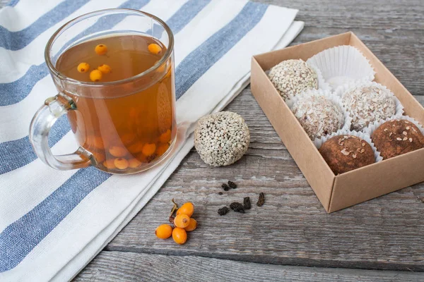 raw vegan energy balls with sea buckthorn tea with honey in a transparent Cup.