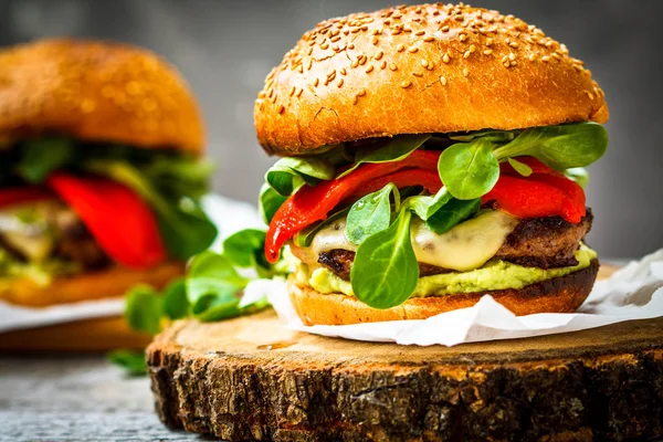 Leckere gegrillte Rindfleisch-Burger mit Käse, Guacamole und eingelegten Paprika. — Stockfoto