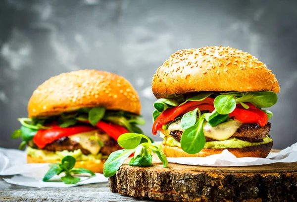 Leckere gegrillte Rindfleisch-Burger mit Käse, Guacamole und eingelegten Paprika. — Stockfoto