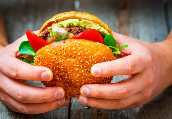 Tasty grilled beef burger in man's hands. — Stock Photo, Image