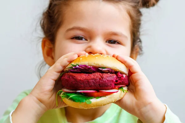 child (girl) eating healthy vegan burger.